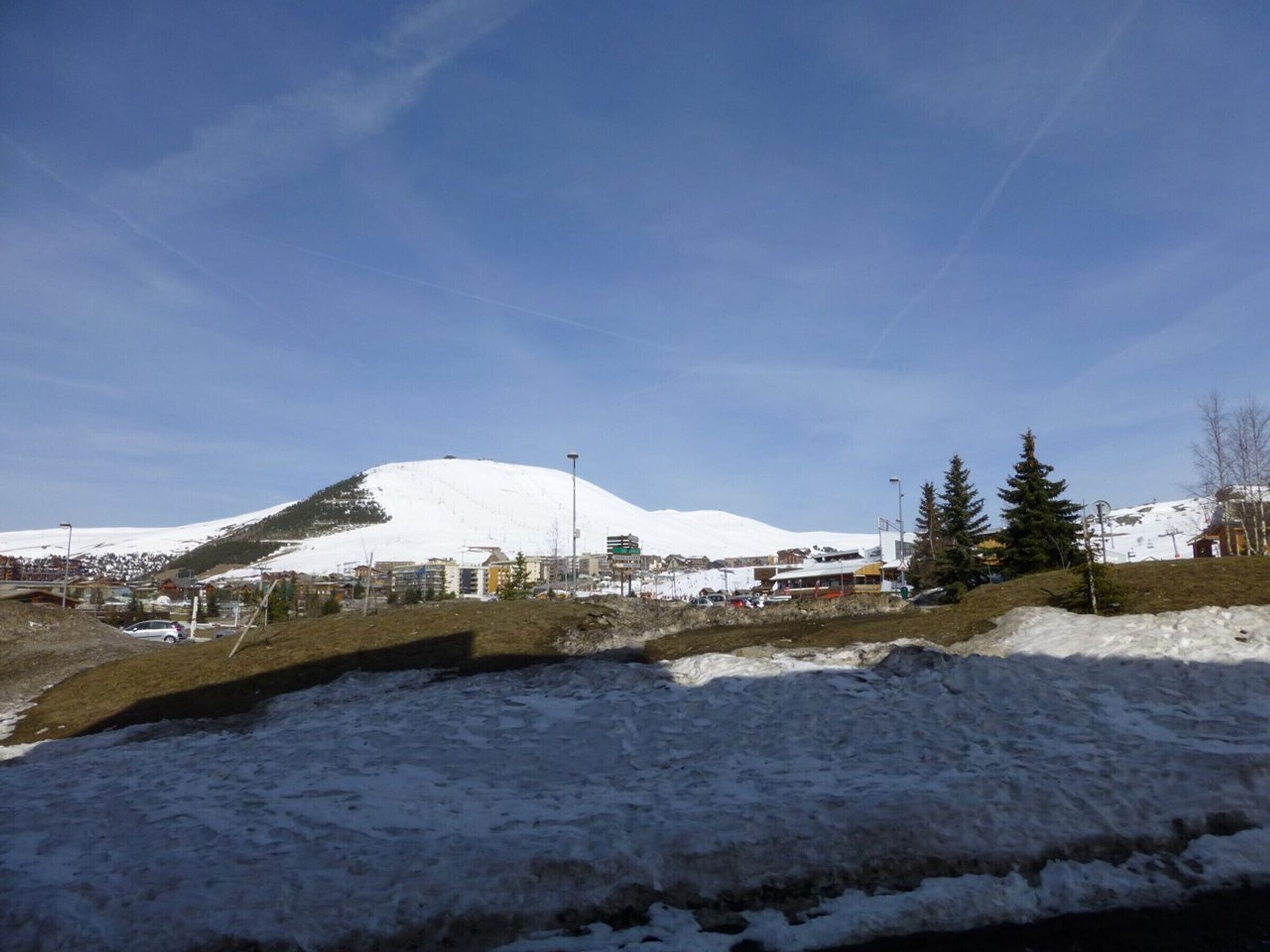 Ein verschneiter Berg mit Gebäuden im Hintergrund.