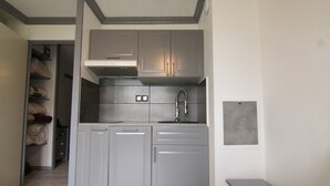 A compact kitchen with grey cabinets, a stainless steel faucet, and a built-in oven.