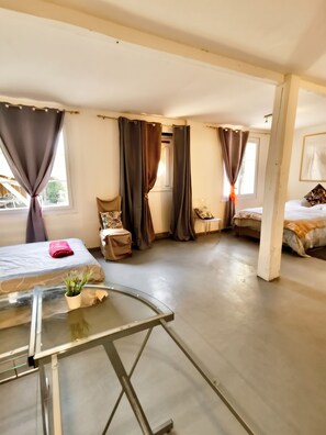 Et moderne hotelværelse med et glasbord, to senge og en stol.