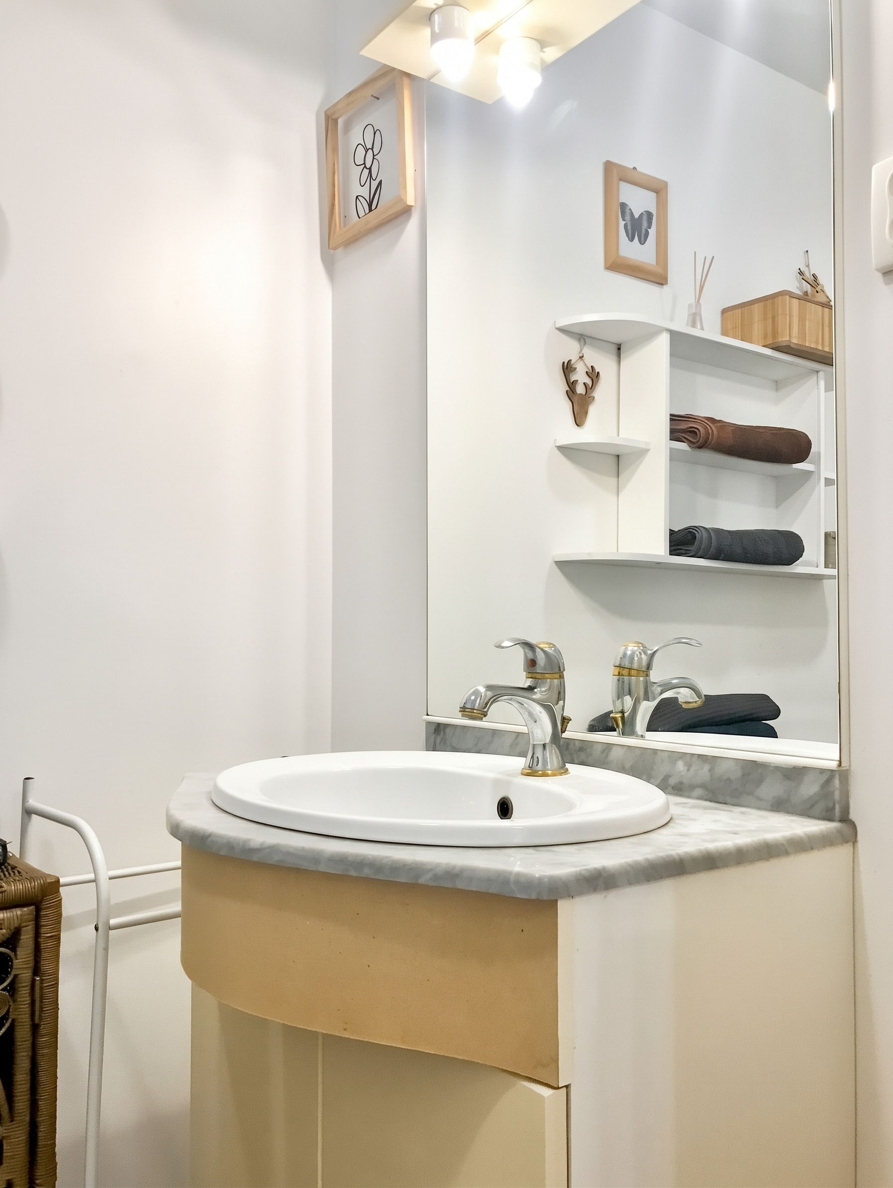 A bathroom with a white sink, a mirror, and a shelf with toiletries.