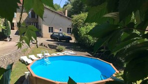 Ein Pool im Freien mit einer Leiter, umgeben von Liegestühlen und einer Steinmauer.