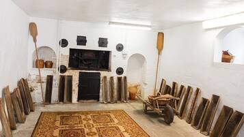 A room with a large patterned rug, a fireplace, and various wooden objects.