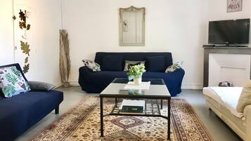 En stue med sofa, sofabord, et mønstret tæppe og et fjernsyn.