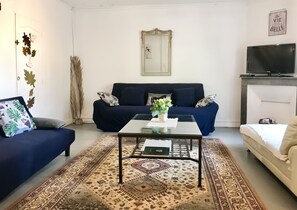 Ein Wohnzimmer mit einer Couch, einem Couchtisch, einem gemusterten Teppich und einem Fernseher.