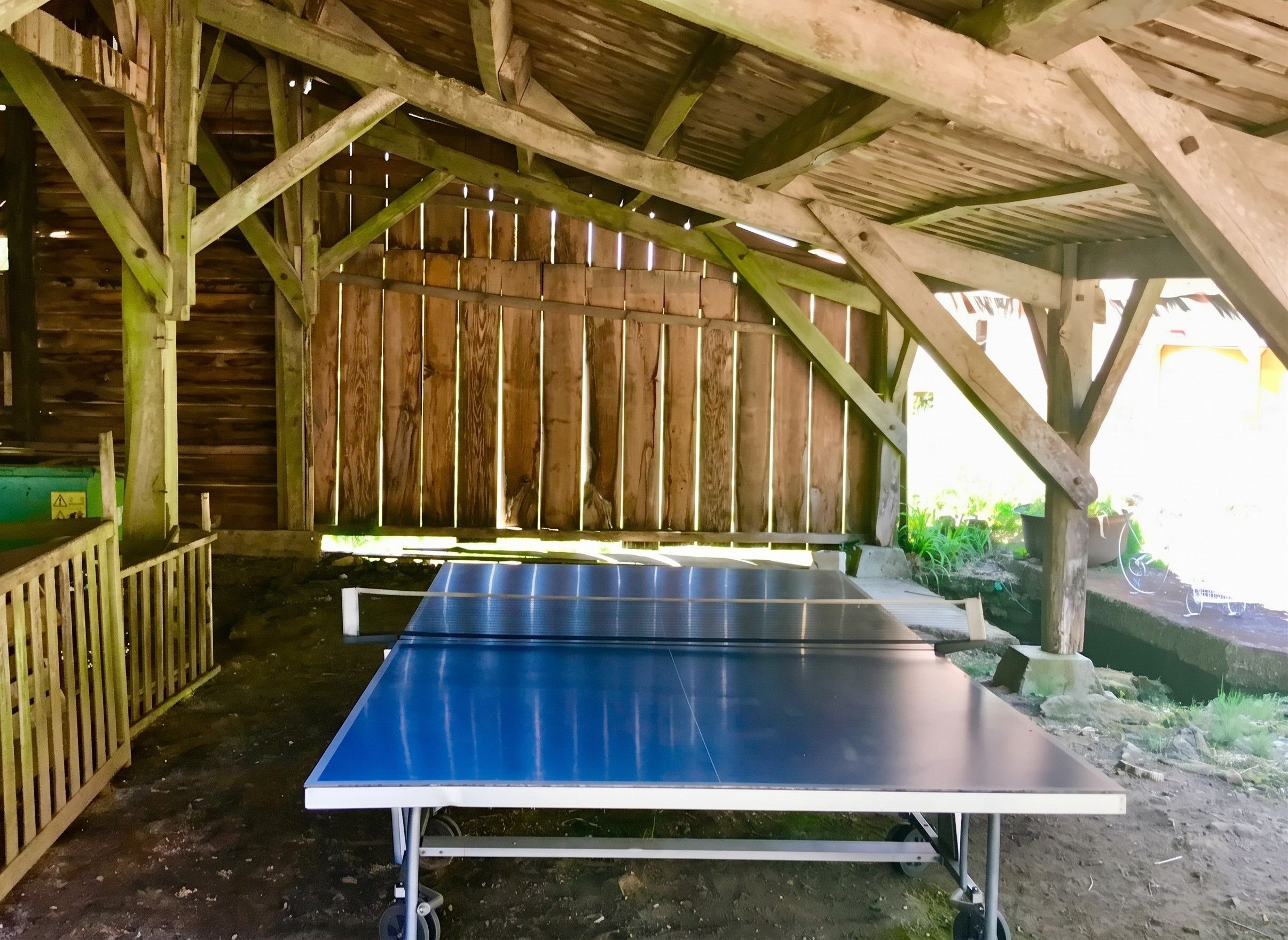 Une table de ping-pong placée sous une structure en bois dotée d’un toit incliné.