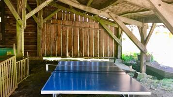 Une table de ping-pong placée sous une structure en bois dotée d’un toit incliné.
