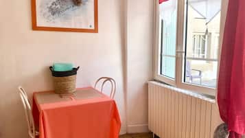 Une petite pièce avec une table, une chaise, un radiateur et une fenêtre donnant sur un paysage agréable.