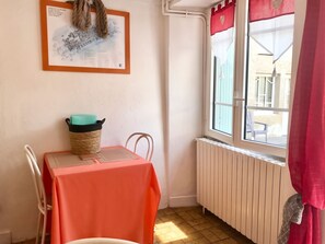 Ein kleiner Raum mit Tisch, Stuhl, Heizkörper und einem Fenster mit Blick.