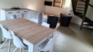 Eine kleine Küche mit Holztisch und weißen Stühlen, ein Essbereich und eine Treppe.