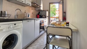 Cocina compacta con lavadora, microondas y cafetera.