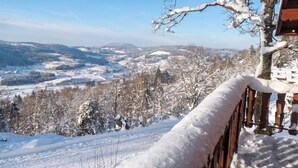 Schneebedeckte Landschaft mit Holzwertlauf und Blick auf eine Stadt in der Ferne.