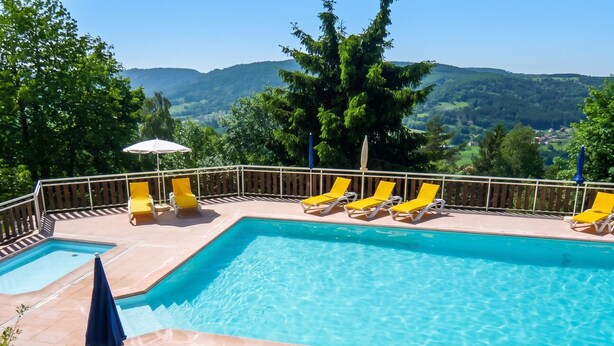 Ein rechteckiger Swimmingpool mit klarem, blauem Wasser, umgeben von gelben Liegestühlen und einem Holzterrasse.