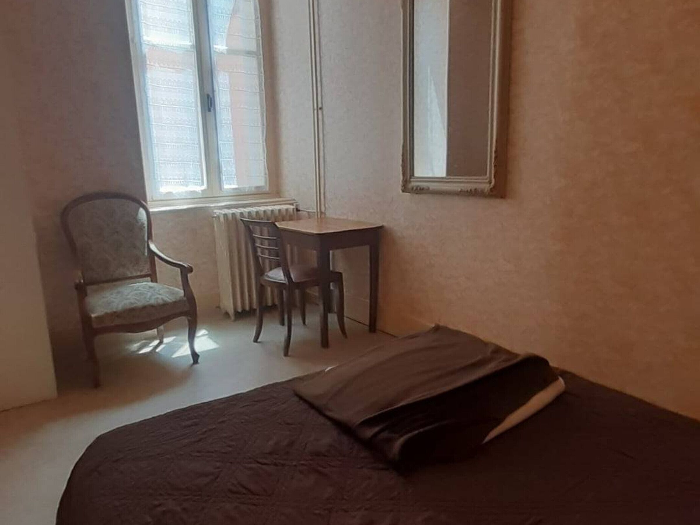 A small room with a bed, a chair, a table, and a window.