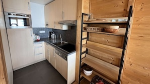 Uma cozinha compacta com eletrodomésticos modernos, armários de madeira e um aparador embutido.