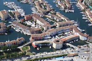 A marina with numerous boats docked, surrounded by historic buildings with a central archway. - Close to the center 4 persons house  et  15m mooring (PORT GRIMAUD)