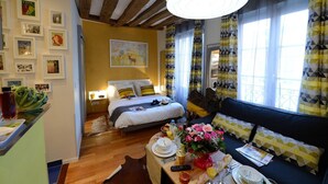 A cozy room with a bed, a sofa, a dining table with breakfast, and a large window with curtains. - A2DF Boogie-Woogie (París)
