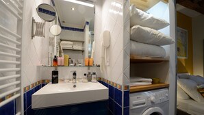 A bathroom with a white sink, blue-tiled walls, a mirror, a hairdryer, and a washing machine. - A2DF Boogie-Woogie (París)