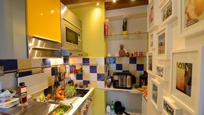 A compact kitchen with a microwave, stove, and various kitchen utensils. There are framed pictures on the walls and a small refrigerator. - A2DF Boogie-Woogie (París)