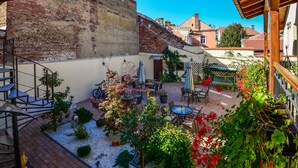Un patio con mobiliario exterior, una escalera y un muro de ladrillo.