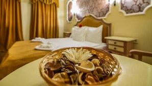Una habitación de hotel con una cama, una mesita de noche, un armario pequeño y un tazón de nueces sobre una mesa.