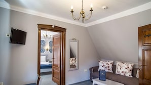 Una habitación acogedora con un sofá, una mesita, un espejo y un televisor.
