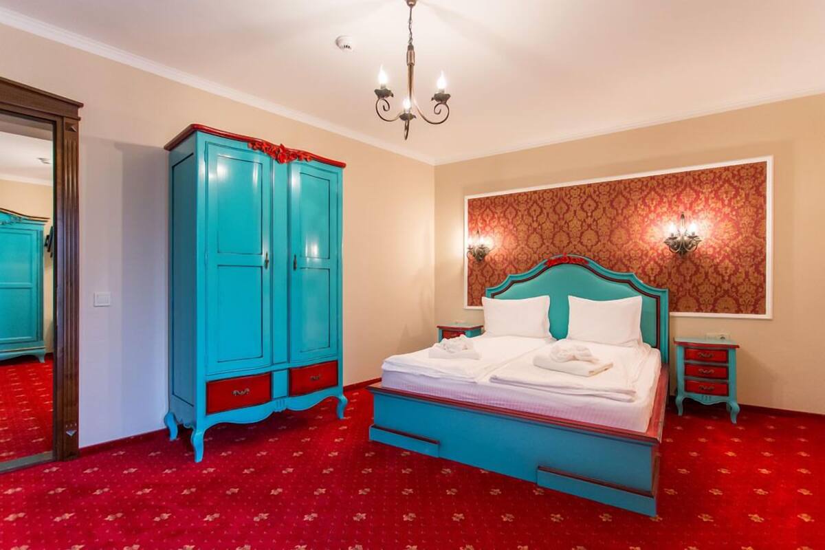 Un dormitorio con cama, armario, espejo y papel tapiz estampado.