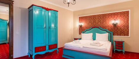 Un dormitorio con cama, armario, espejo y papel tapiz estampado.