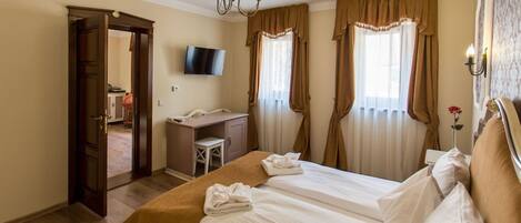 Une chambre d’hôtel comprenant un lit, un bureau, une télévision et une porte donnant sur une autre pièce.