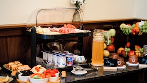 Montaje de bufé con diferentes opciones de comida, un dispensador de bebidas y condimentos.