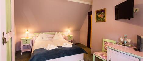 A bedroom with a bed, bedside tables, a dresser, a television, and a painting on the wall.