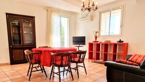 Un comedor con una mesa y sillas, un televisor, un armario rojo y un sofá.