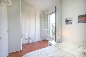 A bedroom with a bed, a chair, a wardrobe, and a window.