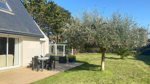 Ein Haus mit einer Terrasse, einem Esstisch und Stühlen.
