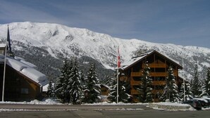 A lodge with a wooden exterior, a ski lift in the background, and snow-covered mountains. - Méribel: Cozy 2-Room Apt, 4 Pax, near Shops and Slopes (Méribel)