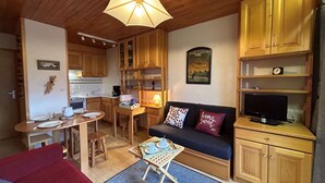 A compact living space with a kitchenette, a dining area, and a seating area with a sofa and a TV. - Méribel: Cozy 2-Room Apt, 4 Pax, near Shops and Slopes (Méribel)