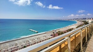 A coastal view with a beach, promenade, and a pier extending into the sea. - N&J - SUITE ROYAL LUXEMBOURG - Rooftop pool (Niza)