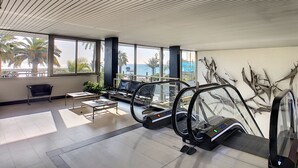 An interior with an escalator, large windows, and a view of palm trees. - N&J - SUITE ROYAL LUXEMBOURG - Rooftop pool (Niza)