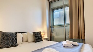 A hotel room with a bed, pillows, a window with curtains, and a nightstand with a lamp. - N&J - SUITE ROYAL LUXEMBOURG - Rooftop pool (Niza)
