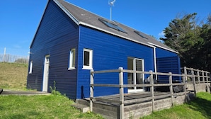 Um edifício azul com um deck de madeira e uma cerca de metal.