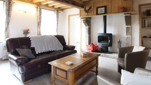 A cozy living room with a leather sofa, a wooden coffee table, and a stone fireplace with a television.