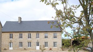 A stone building with a symmetrical facade, multiple windows, and a central entrance.