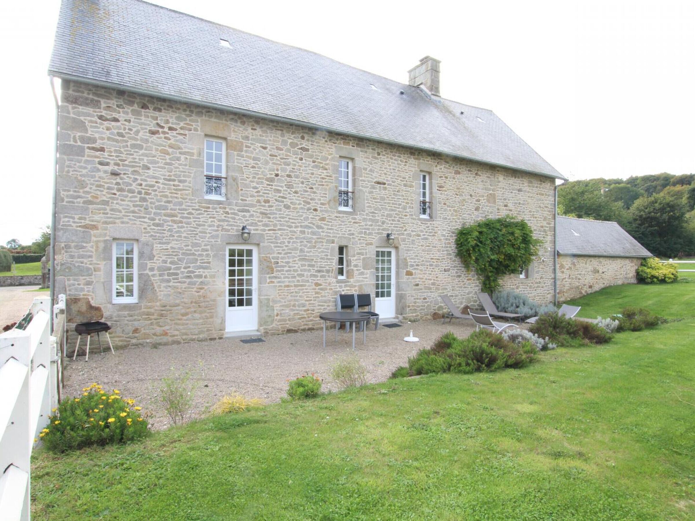 A stone building with a gravel patio, outdoor seating, and a garden.