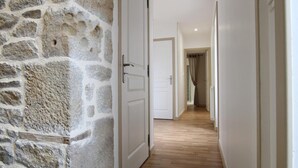 A hallway with a stone wall, wooden flooring, and white doors leading to other rooms.
