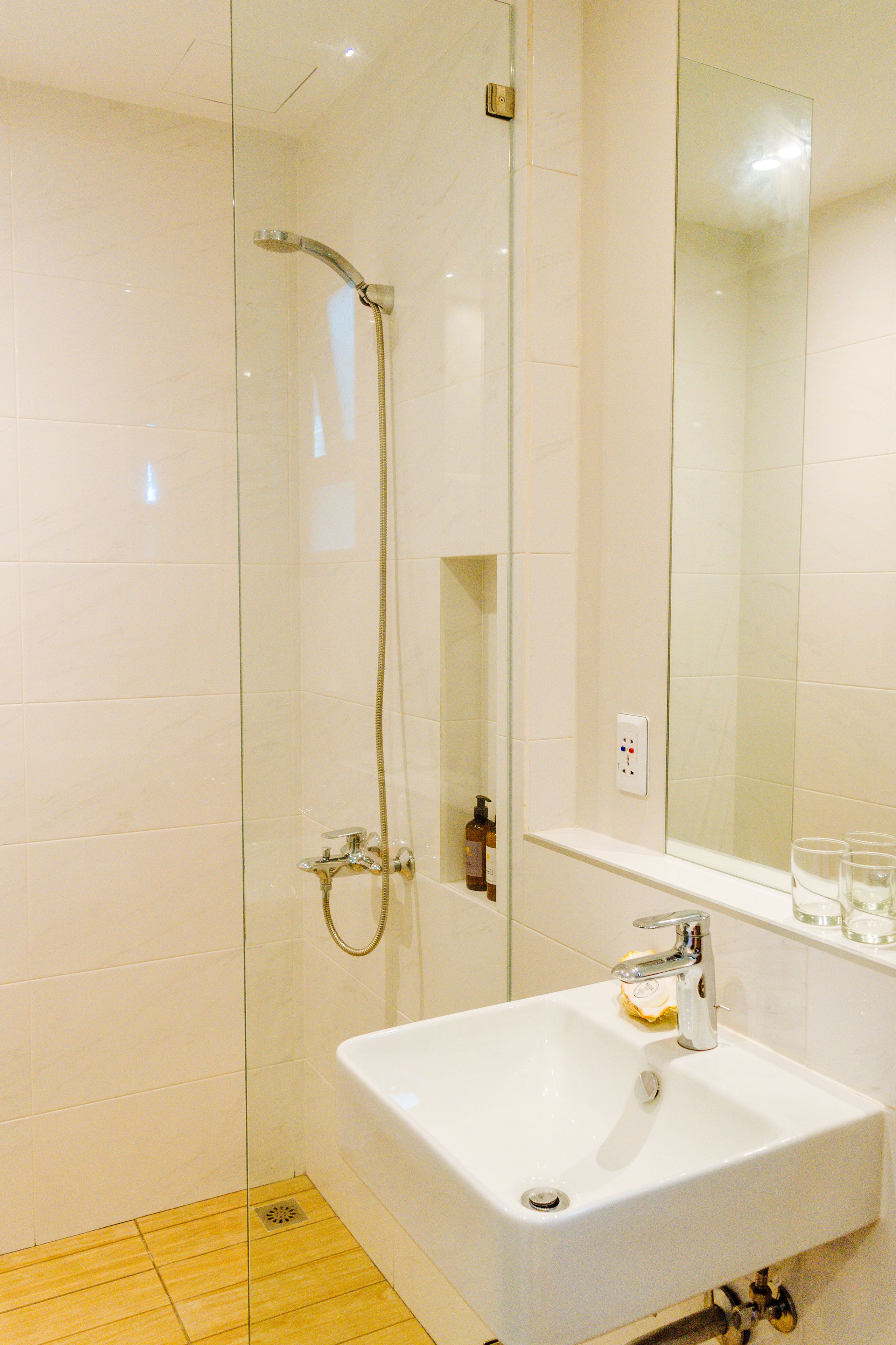 Une salle de bain avec une douche à parois de verre, un lavabo blanc et un miroir au-dessus.