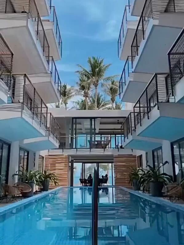 A modern hotel with a central swimming pool, multiple balconies, and palm trees. - Banana Bay Boracay (Boracay Island)