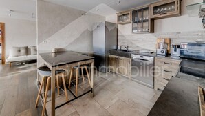 Una cocina moderna con una isla central, taburetes de bar, horno empotrado y una estantería para vinos.