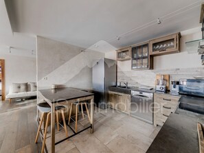 Eine moderne Küche mit Kochinsel, Barhocker, integriertem Backofen und Weinkühler.