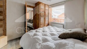 Un dormitorio con cama, armario de madera y ventana con vistas a un paisaje nevado.