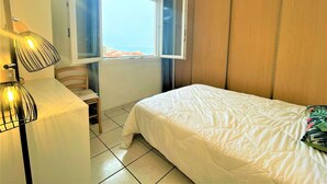 A bedroom with a bed, a window with a view, and a lamp. - Saint-Cyprien: 2-room apartment, sleeps 5, balcony, parking, near beach (Saint-Cyprien)