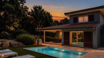Une maison moderne dotée d’une piscine, d’un espace salon extérieur et d’un patio couvert.